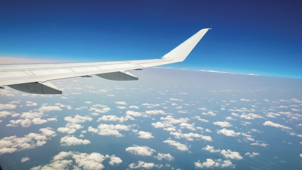 Airplane wing over clouds and blue sky